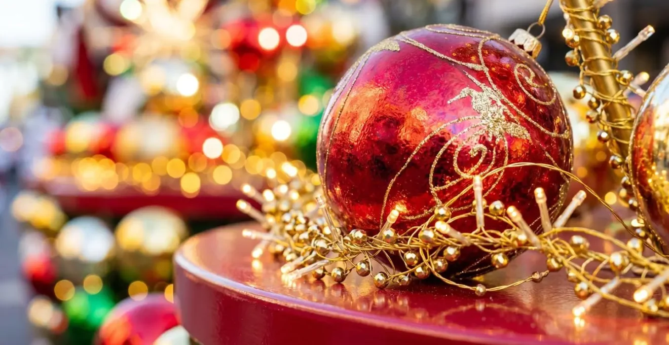 Gros plan sur des guirlandes LED dorées et une boule géante rouge brillante formant une décoration de char de Noël, avec un arrière-plan flouté créant un effet bokeh lumineux